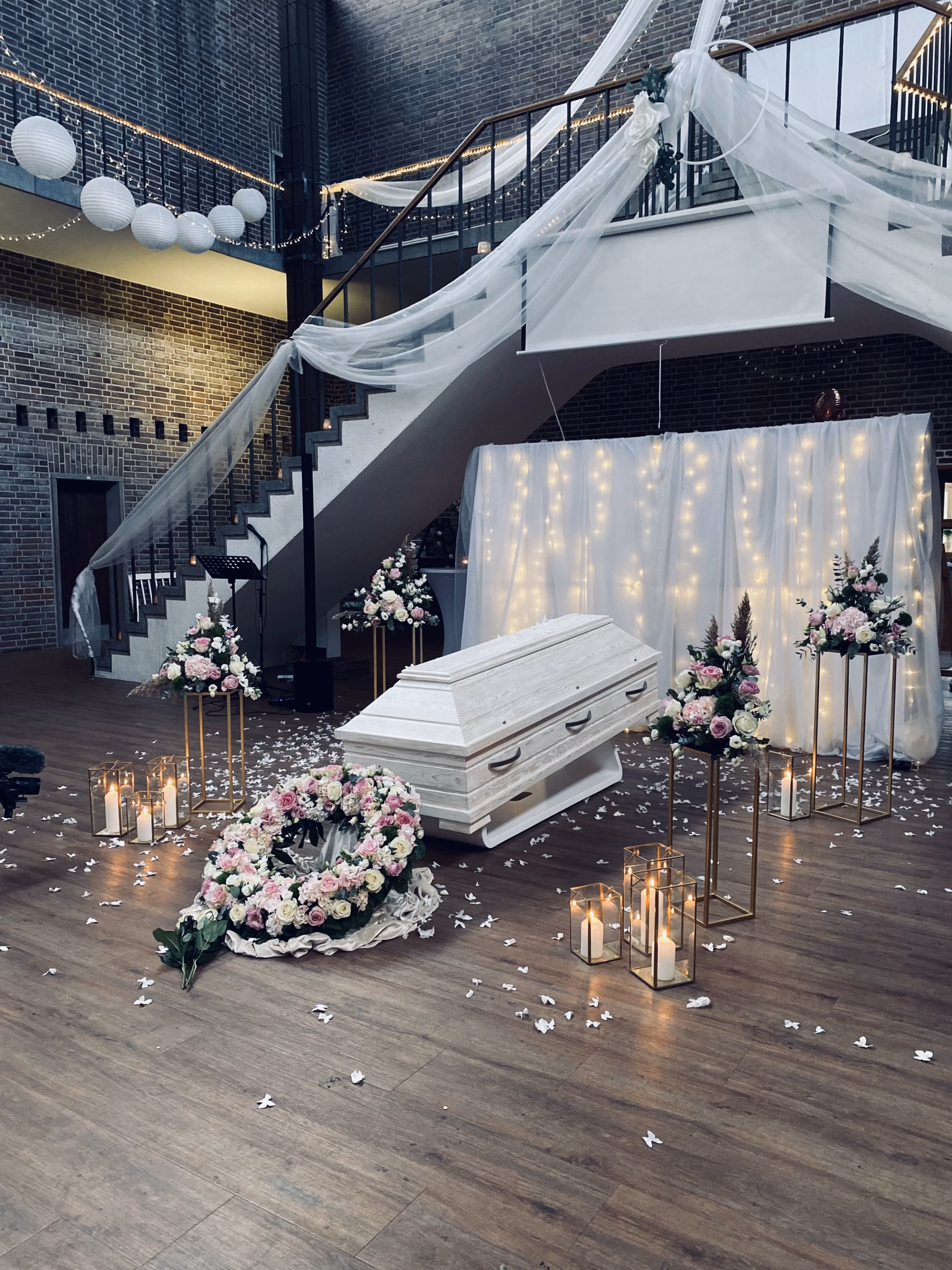 Sarg in Galerie zwischen Blumen und Lichterketten
